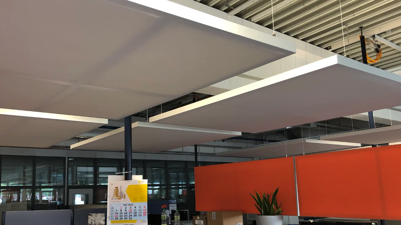 Detailansicht abgehängter Akustik-Deckensegel über dem Service-Desk-Bereich in einer Industriehalle